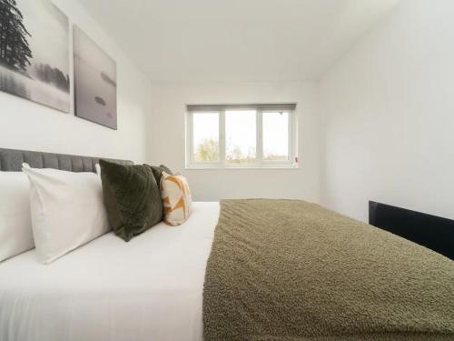 ein weißes Schlafzimmer mit einem Bett mit Kissen und einem Fenster in der Unterkunft Pass the Keys Spacious Wembley Apartment with Free Parking in London