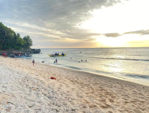 a group of people on a beach with boats in the water at Talim Camp n Sea Beach Camp in Lian