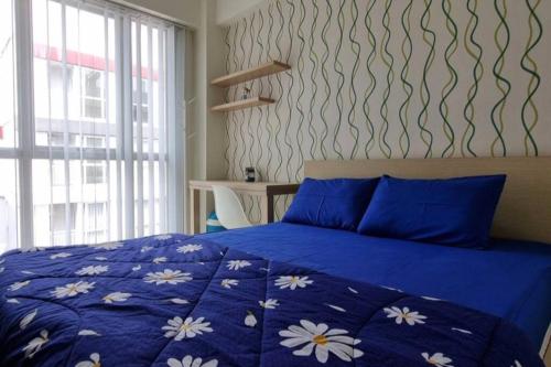 una camera da letto con un letto blu e fiori sopra di Apt Grand Taman Melati 2 Studio UI Depok 5oNy with Netflix a Pondoktjina 1