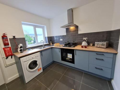 a kitchen with a sink and a washing machine at SleepyStays 3 Bedroom Modern & Central Location Sleeps 4 in Merthyr Tydfil