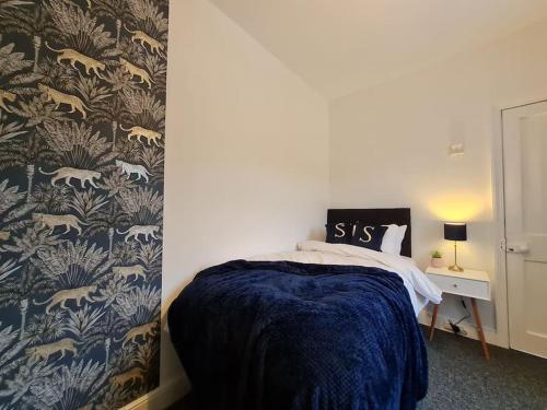 ein Schlafzimmer mit einem Bett mit einer blauen Decke in der Unterkunft SleepyStays 3 Bedroom Modern & Central Location Sleeps 4 in Merthyr Tydfil