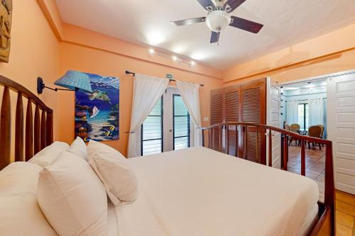 a bedroom with a bed with a ceiling fan and a window at Condo #24 @ Beachside Villas in Placencia Village