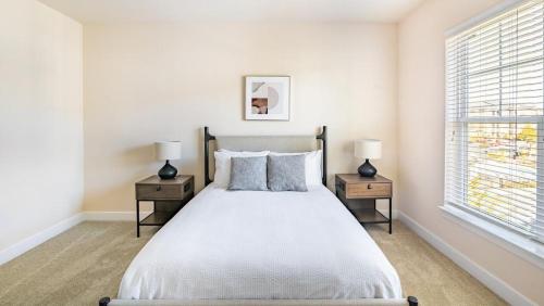 ein weißes Schlafzimmer mit einem Bett und zwei Nachttischen in der Unterkunft Landing Modern Apartment with Amazing Amenities (ID9174X16) in Fredericksburg
