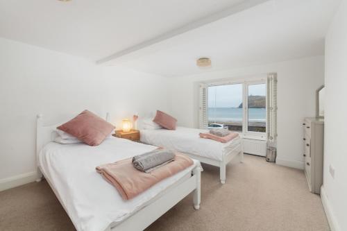 two beds in a room with a view of the ocean at Seaview on the beach in Port Erin