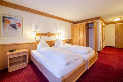 a bedroom with a large bed with white sheets at Hotel Grindelwalderhof in Grindelwald