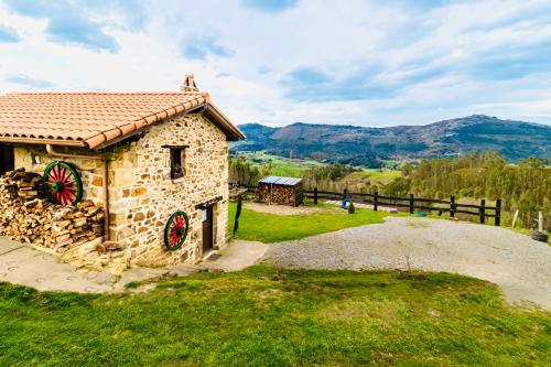 a stone house with a red roof on a hill at Casa rural La alemana in Liérganes