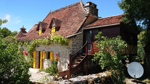 una vecchia casa con finestre gialle e scala di Chambres d'hôte Mas de Bouzou a Grèzes
