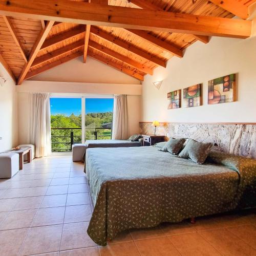 a bedroom with two beds and a large window at Posada La Soñada in Villa General Belgrano
