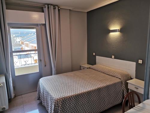 a small bedroom with two beds and a window at hostal san francisco in Puebla de Sanabria