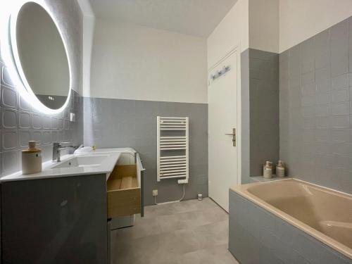 a bathroom with a sink and a tub and a mirror at Le P’tit B - Quartier Saint-Michel/Centre Ville in Saint-Brieuc