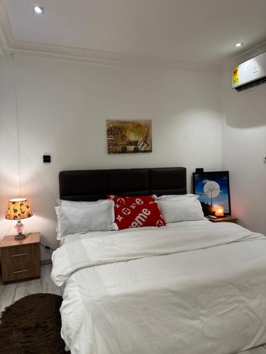 a bedroom with a large white bed with a red pillow at Rich homes in Baatsona