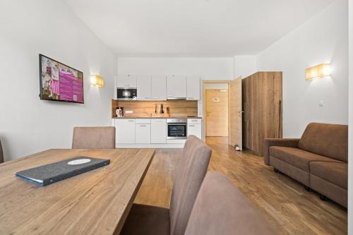 a living room with a wooden table and a kitchen at Landhotel Berger in Eben im Pongau