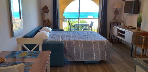 a living room with a blue couch and a table at Studio standing classé avec terrasse vue mer " les pieds dans l'eau " à Algajola in Algajola