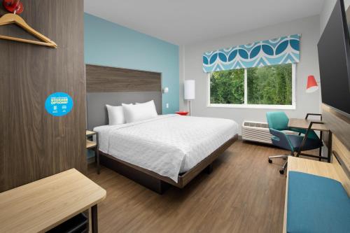 a bedroom with a bed and a chair and a window at Tru By Hilton Jacksonville Airport in Jacksonville