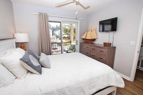 Schlafzimmer mit einem Bett, einem TV und einem Fenster in der Unterkunft M24, Sunshine and Tan Lines- Oceanside, Community Pools in Corolla
