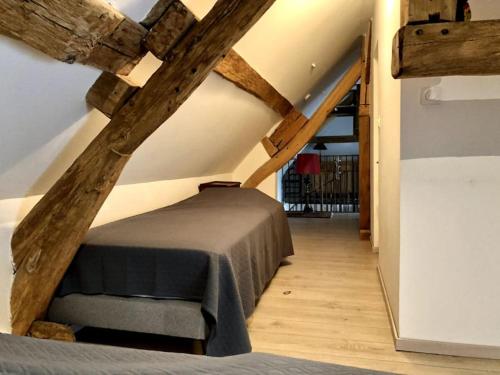 Cette chambre mansardée dispose d'un lit et de poutres apparentes. dans l'établissement maison de ville agréable La roseraie Musicale, à Mer