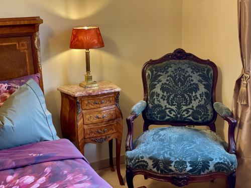 um quarto com uma cadeira e um candeeiro ao lado de uma cama em Chateau Masburel em Fougueyrolles