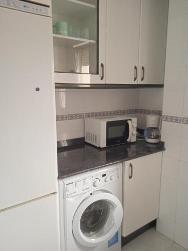 a kitchen with a washing machine and a microwave at Mar de Gala in Suances