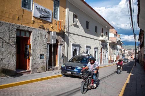 two people riding bikes down a street with a car at Hospedaje Tel Aviv in Ayacucho