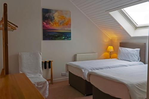 a bedroom with two beds and a table and a skylight at Newton Hall in Inveraray