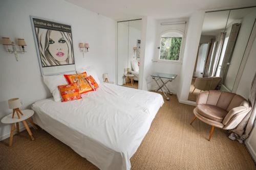 une chambre avec un lit blanc et une chaise dans l'établissement Maison de charme au cœur du golfe de Saint-Tropez, à Gassin