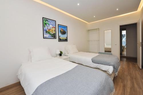 two beds in a room with white walls and wood floors at Dream In Cascais - Checkinhome in Cascais