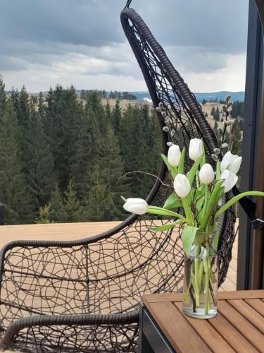 a glass vase with white flowers on a table at Natura Tiny House in Mărişel