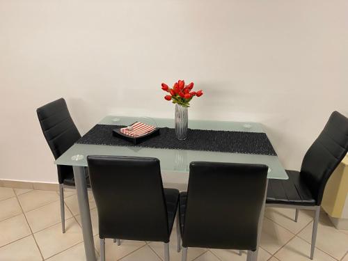 a table with chairs and a vase of flowers on it at Elíxir Apartman Hajdúszoboszló in Hajdúszoboszló