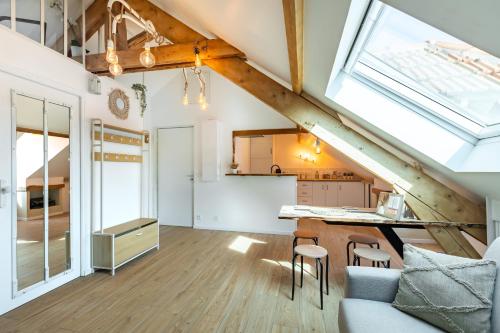 Il comprend une cuisine mansardée et un salon avec une grande fenêtre. dans l'établissement T2 cosy et chic près de la Défense et de Paris, à Maisons-Laffitte