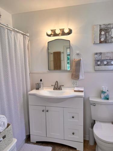 La salle de bains blanche est pourvue d'un lavabo et d'un miroir. dans l'établissement Across The INN Entire 3 bedrooms Colonial House with lovely porch and extremely fast Wi-Fi, à Washington, Virginia