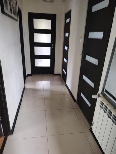 a hallway with black doors and a tile floor at U Zajączka in Busko-Zdrój