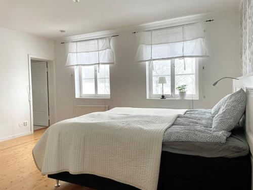 a bedroom with a large bed with two windows at Timrå Farmhouse in Timrå