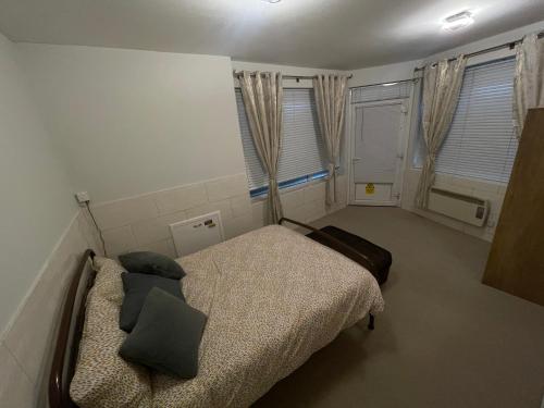 a small bedroom with a bed and two windows at Beanies LorneStreet Four Bed House in Swindon