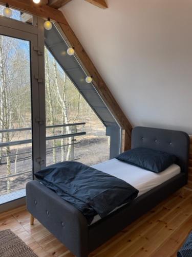 a bed in a room with a large window at Domki Plaża Kownatki VIP in Kozłowo