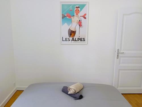 a hat on a bed in a room with a poster at 102 - Appart rénové avec grand salon et 1 chambre - Tram et Clinique Mutualiste à 1 min in Grenoble