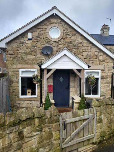 a stone house with a blue door and a fence at The Old Bakery in Gateshead