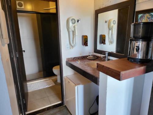 een badkamer met een wastafel, een toilet en een spiegel bij La Roca Studio 6 in Praia do Rosa