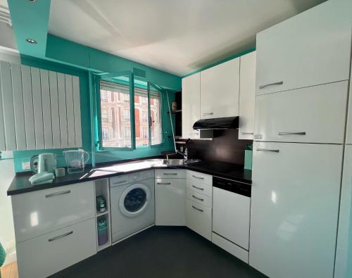 une cuisine avec des armoires blanches et une machine à laver dans l'établissement Cozy Studio near Tour Eiffel, à Paris