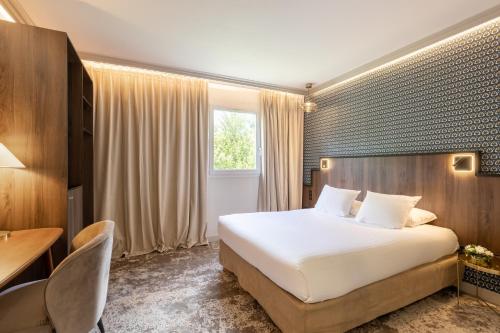 プロエルメルにあるLancelot & Spa - Domaine du Roi Arthurのベッド、テーブル、椅子が備わるホテルルームです。