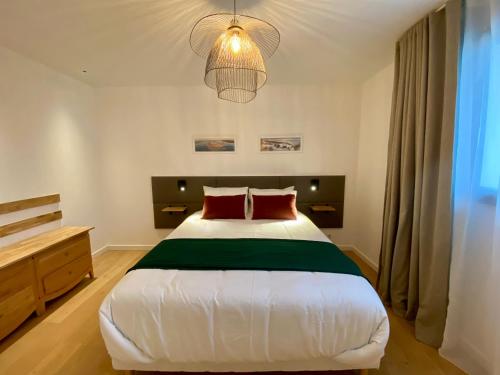 1 dormitorio con 1 cama blanca grande con almohadas rojas en La villa du golf en Gujan-Mestras