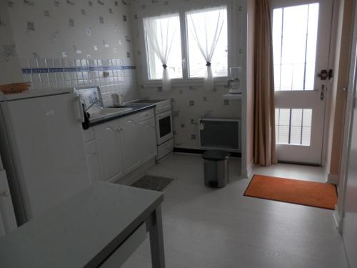  La cuisine est équipée de placards blancs et d'un réfrigérateur. dans l'établissement Les Fauvettes, à Royan