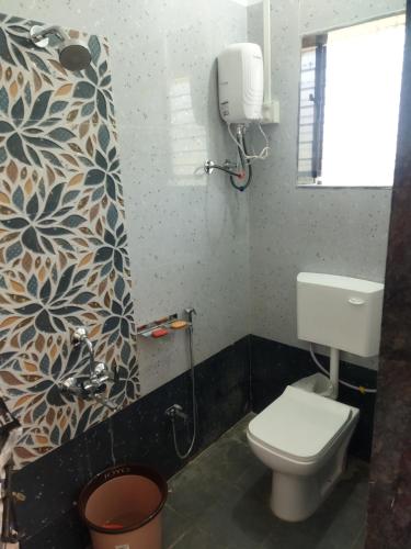 baño con aseo blanco y ventana en Swamiraj home stay en Ratnāgiri