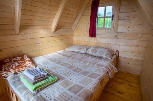 a bed in a log cabin with a window at Maple bungalows in Žabljak