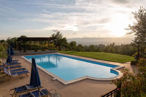 a swimming pool with chairs and umbrellas on a patio at Agriturismo Cornieto in Monteleone dʼOrvieto