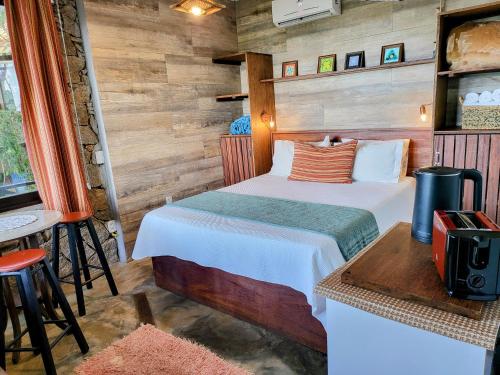 a bedroom with a bed in a room with wooden walls at La Roca Studio 6 in Praia do Rosa