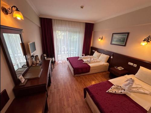 a hotel room with two beds and a desk at STELLA HOTEL&Spa ALL INCLUSIVE in Antalya