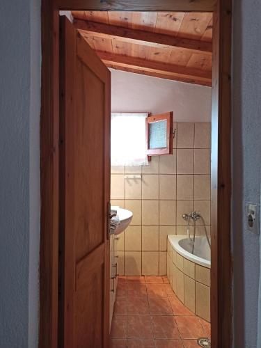 een badkamer met een bad, een wastafel en een deur bij Casa de la Fuente in Ditropo