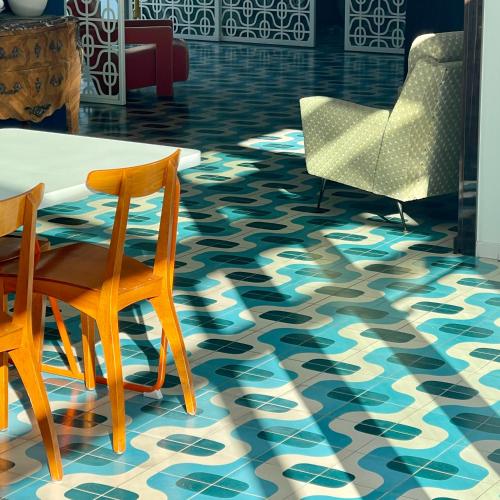 a room with a table and two chairs and a floor with blue at Hôtel Saint-Clair, côté Plage in La Grande Motte