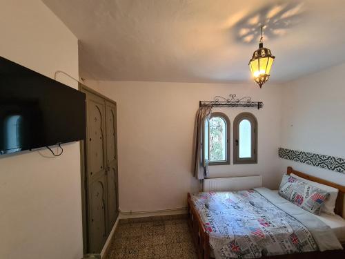 a bedroom with a bed and a tv and a window at Maison d'hôte Bousaid in Chefchaouene