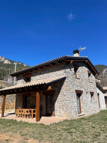 a stone building with a table and chairs in front at Casa de la Mestra, Espinalbet - ALBERGA in Castellar del Riu